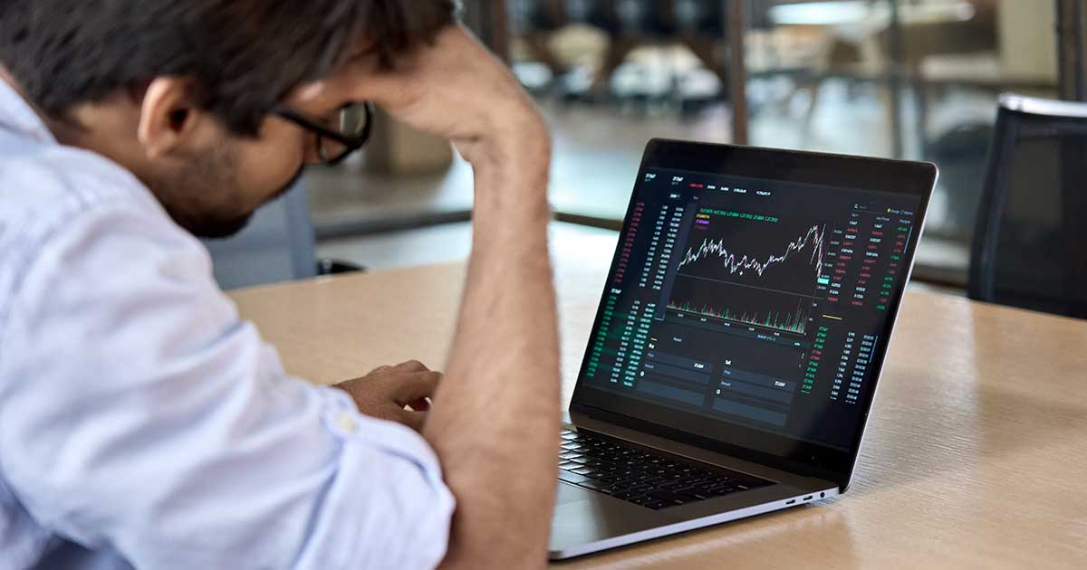 Depressed man looking at data graphic on laptop computer