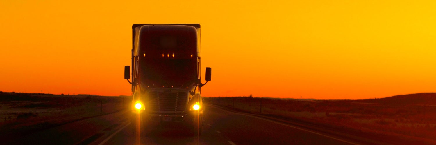 Truck driving on road during sunset